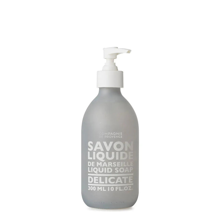 A 10oz glass pump bottle of COMPAGNIE DE PROVENCE - SAVON LIQUID DE MARSEILLE DELICATE by CIE LUXE BRANDS, featuring white text and a white dispenser, crafted with botanical oils for a gentle cleanse.