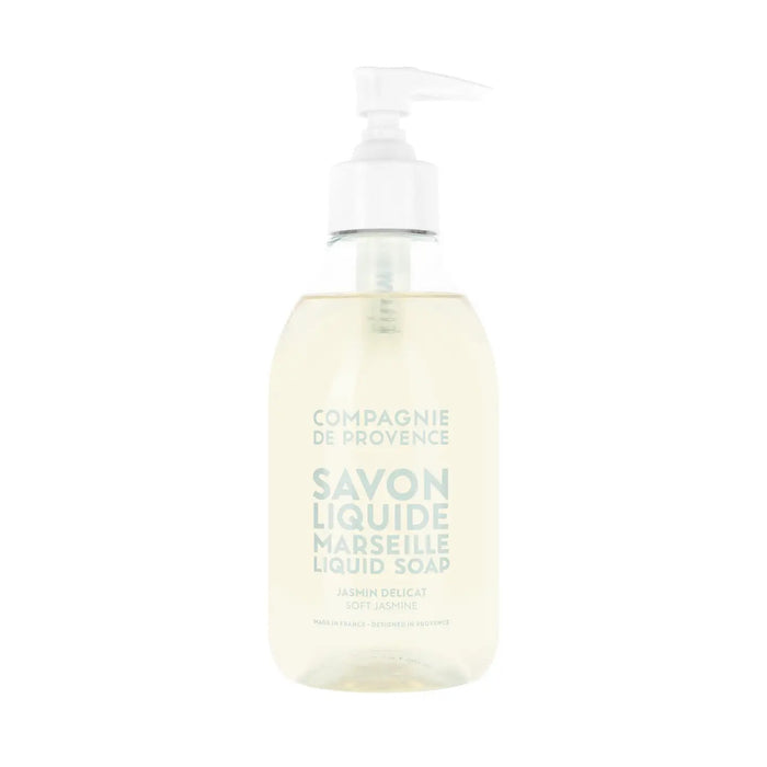 A clear pump bottle of COMPAGNIE DE PROVENCE - SAVON LIQUIDE DE MARSEILLE SOFT JASMINE 10OZ by CIE LUXE BRANDS, with light beige liquid and light blue label text, enriched with nourishing botanical oils.