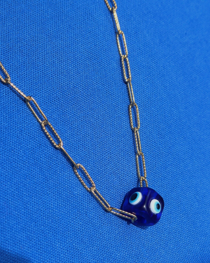 Necklace with a blue evil eye cube charm pendant on a gold paperclip chain made in Greece; Greek evil eye jewelry