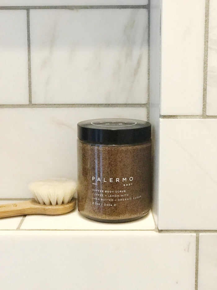 A clear jar with a black lid holds PALERMO BODY’s COFFEE & LEMON BODY SCRUB, an exfoliating sugar scrub with shea butter and organic sugar (8.5oz/240g). The brown, granular formula is a favorite for cellulite treatment.