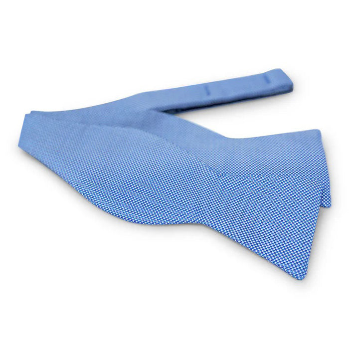 The PETER-BLAIR - ELBOW BEACH SILK BOW TIE IN BLUE by BIRD DOG BAY features a blue woven silk with a small white checkered pattern, adjustable neck, and is expertly crafted for timeless style.