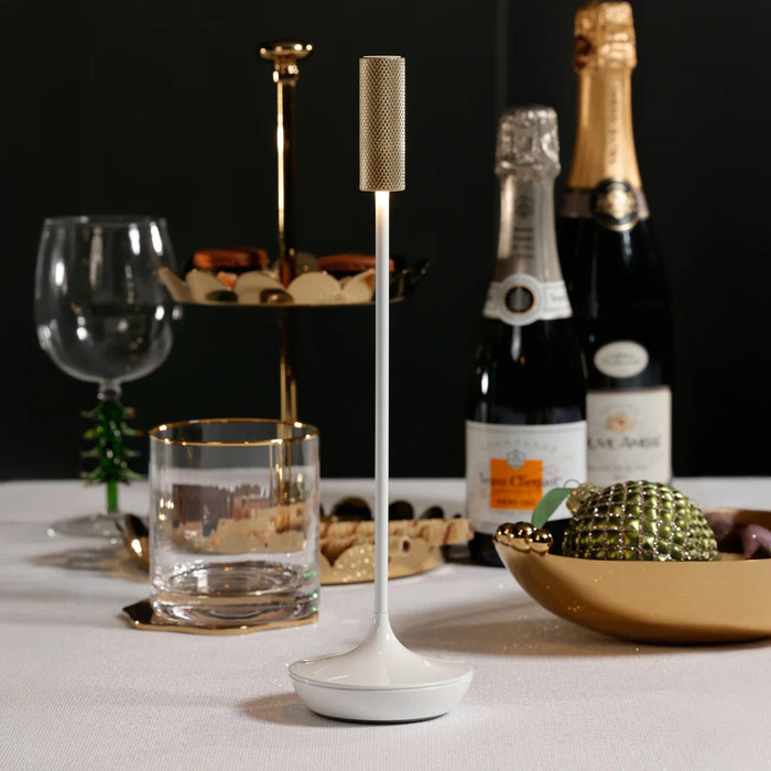 The SLEEK RECHARGEABLE TABLE LIGHT by ZODAX features a modern, minimalist design with a white base and pole, topped with a textured metallic cap. Its waterproof construction ensures lasting durability.