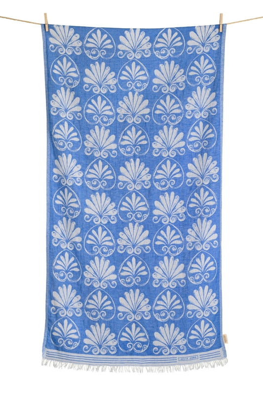Blue cotton beach towel with white Anthemion pattern hanging on a line
