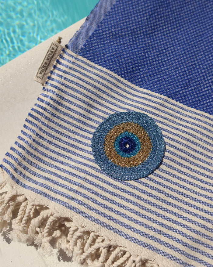 Blue and off-white striped cotton pestemal towel with an embroidered metallic evil eye and fringe trim made in Greece, Greek beach towel by Aelia Anna