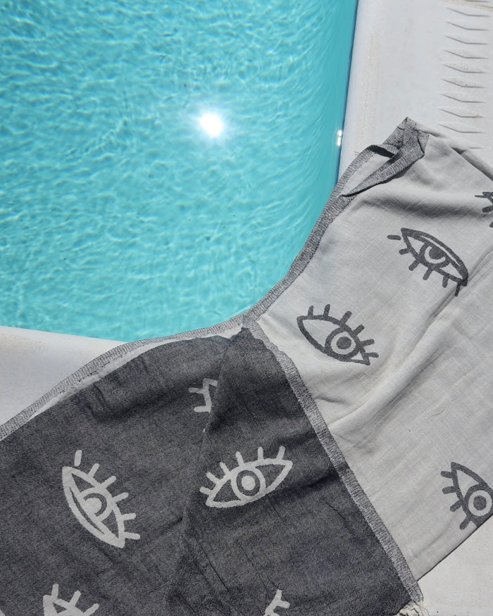 Reversible off-white/light gray towel with evil eye print; drk gray/black cotton pestemal with white eye print