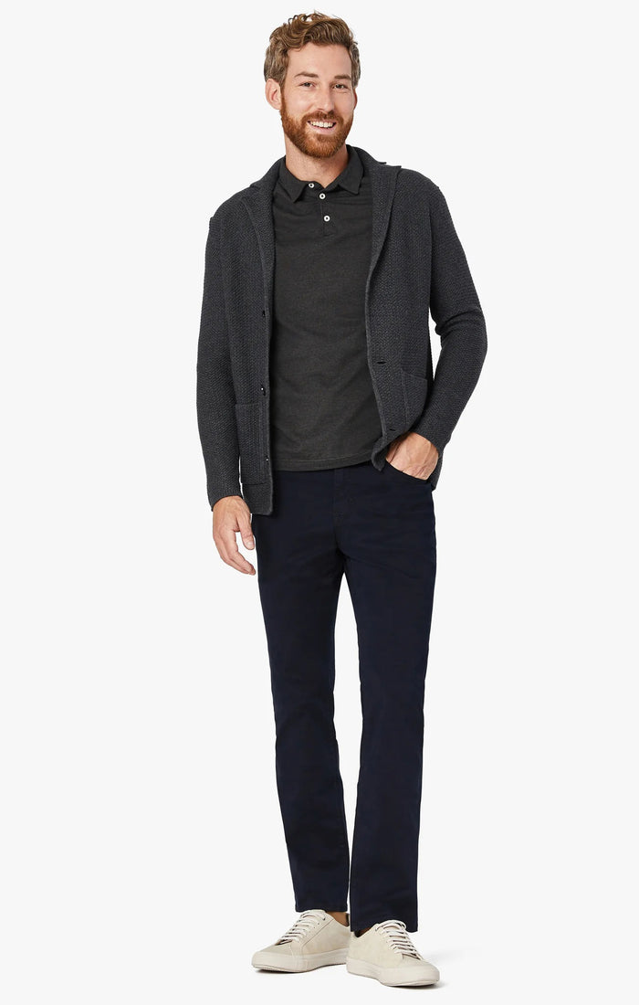 A man stands with his arms crossed, wearing a dark gray T-shirt and 34 HERITAGE - CHARISMA RELAXED STRAIGHT PANT IN NAVY TWILL, with only his upper body and waist shown against a plain white background.