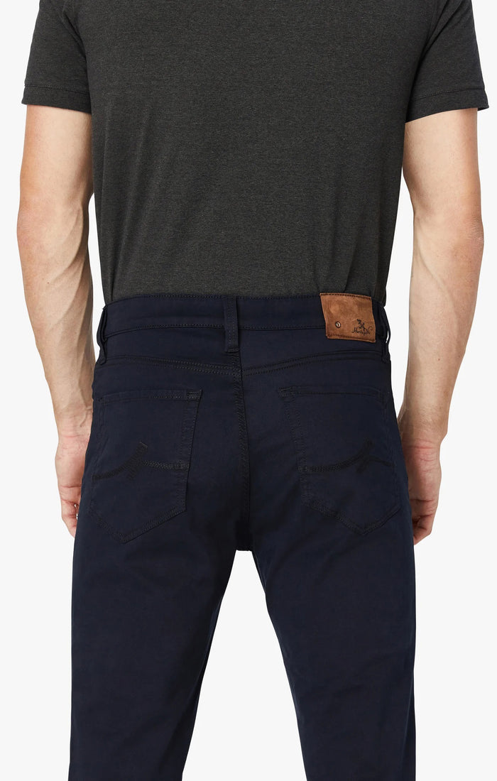 A man stands with his arms crossed, wearing a dark gray T-shirt and 34 HERITAGE - CHARISMA RELAXED STRAIGHT PANT IN NAVY TWILL, with only his upper body and waist shown against a plain white background.