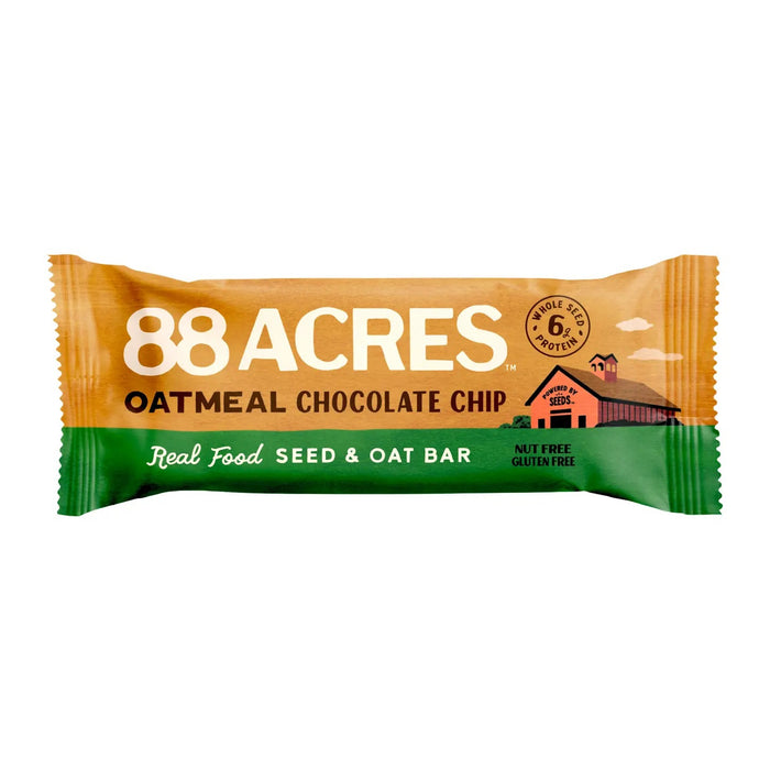 An 88 ACRES - OATMEAL CHOCOLATE CHIP SEED OAT BAR is shown on a light wooden surface, its brown and white wrapper featuring oats, chocolate chips, and Australian sea salt for a chewy cookie bar experience.