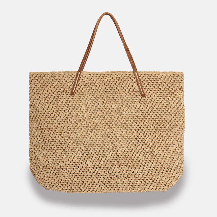 The SANS ARCIDET BEBY LACY RAFFIA TOTE is a large woven basket bag from Madagascar with brown leather straps, shown on a white background—ideal as a summer accessory.