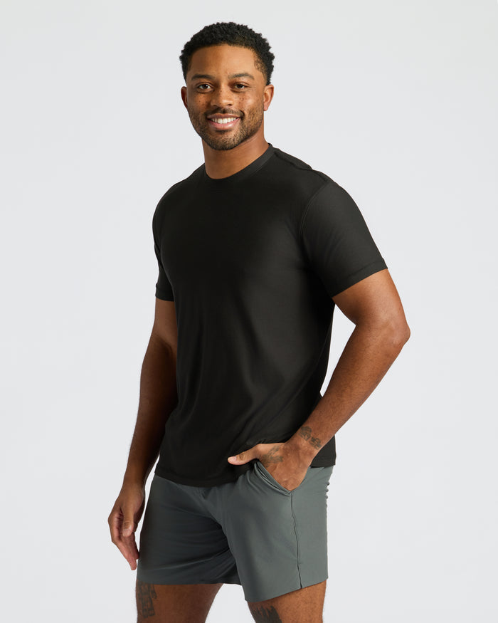 Man modeling Black Active Crew Neck Tee with grey shorts, smiling.