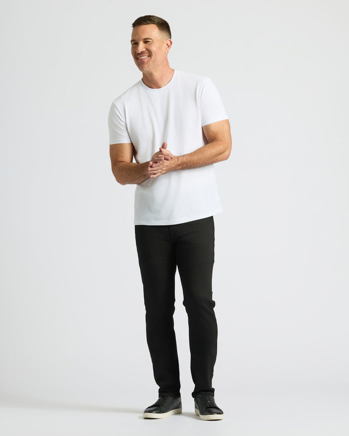 Man wearing Black Wash Straight Comfort Stretch Jeans, white T-shirt, smiling, gesturing.