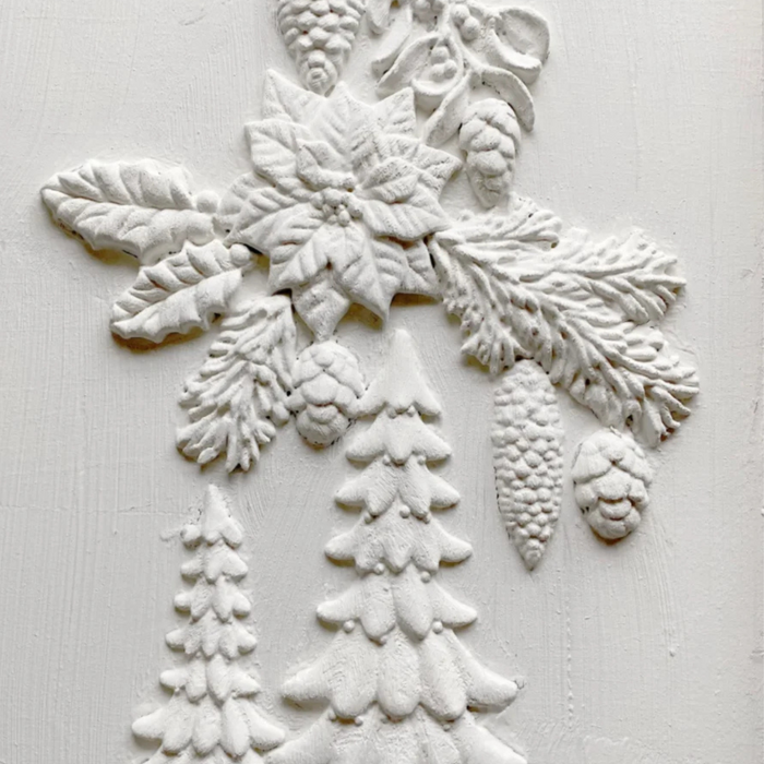 White embossed holiday wall decor featuring a poinsettia, holly, pinecones, and snowflake designs on a textured white background.