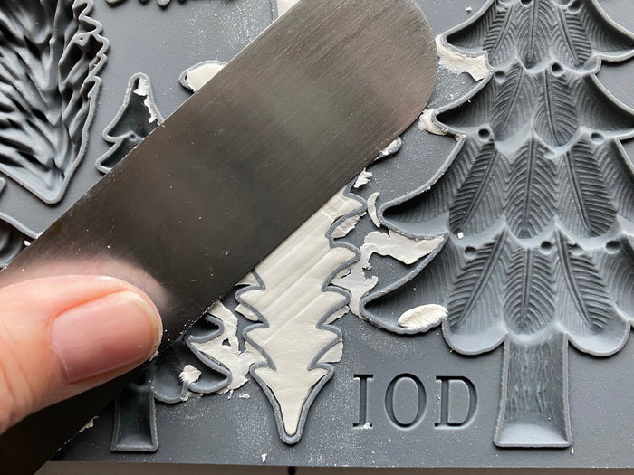 Metal engraving tool being used on a metal surface with engraved designs and 'IOD' branding.