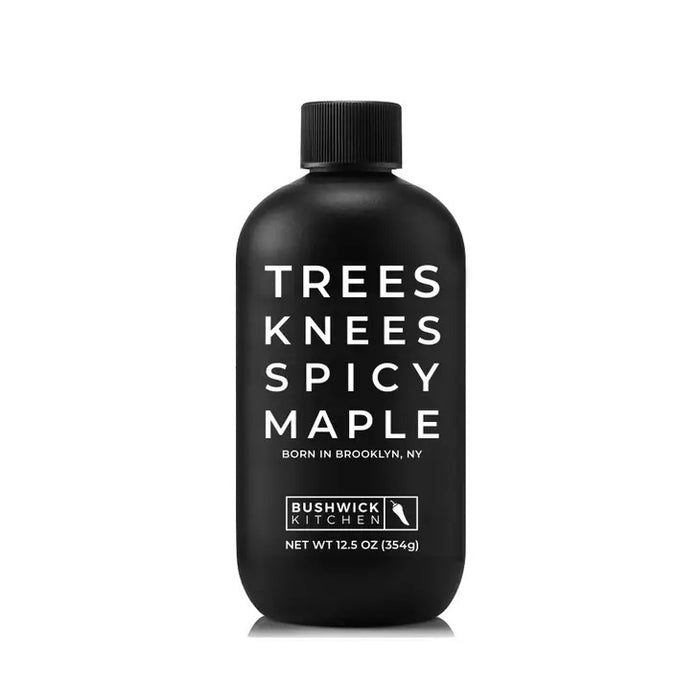 A 12.5 oz (354g) black bottle of BUSHWICK KITCHEN - 'TREES KNEES' SPICY MAPLE SYRUP features white text, a Brooklyn skyline graphic, and a black cap, containing habanero-infused spicy maple syrup.
