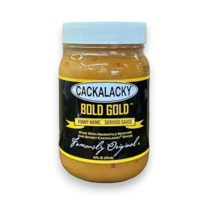 A 16 fl oz (473 ml) jar of CACKALACKY - BOLD GOLD SAUCE from the brand CACKALACKY features a yellow label and a white lid. The label reads, "Funny Name • Serious Sauce. Made with Homestyle Mustard and Secret Cackalacky Spice. Famously Original." This sauce is perfect for any Carolina cookout.