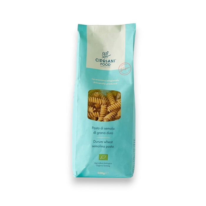 A turquoise bag of Atalanta Corporation's Cipriani Organic Durum Wheat Fusilli, 500g, features a clear window displaying spiral-shaped pasta made from Italian organic semolina. The bag has a white label on top and text in both Italian and English, set against a plain white background.