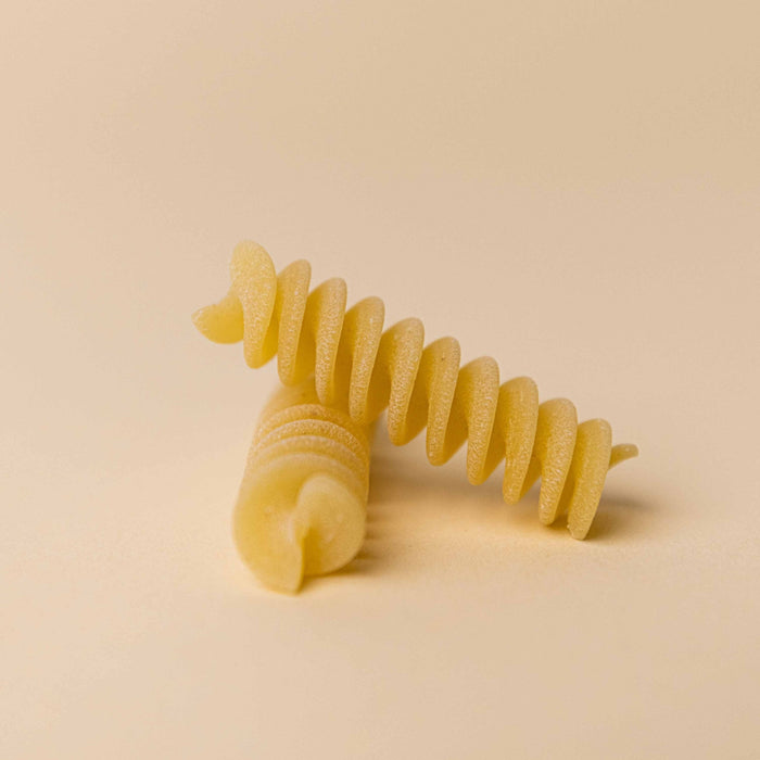 A turquoise bag of ATALANTA CORPORATION CIPRIANI - ORGANIC DURUM WHEAT FUSILLI stands upright on a white background, with the high protein pasta made using a traditional copper die visible through a clear window on the front.