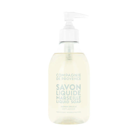 A clear pump bottle of COMPAGNIE DE PROVENCE - SAVON LIQUIDE DE MARSEILLE SOFT JASMINE 10OZ by CIE LUXE BRANDS, with light beige liquid and light blue label text, enriched with nourishing botanical oils.