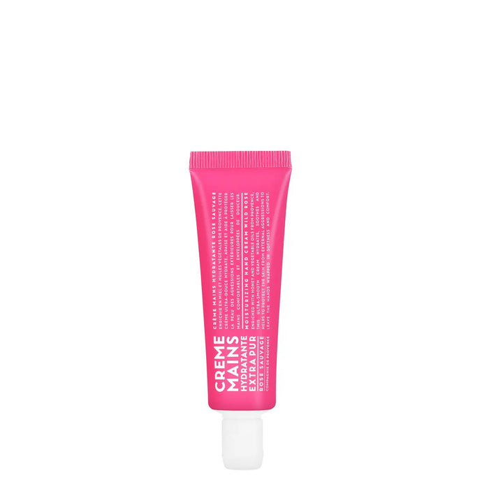 A small, bright pink tube of COMPAGNIE DE PROVENCE Travel Hand Cream Wild Rose 1oz by CIE LUXE BRANDS stands upright on a white background, featuring hydrating formula, subtle rose scent, white cap at the bottom, and white front text.