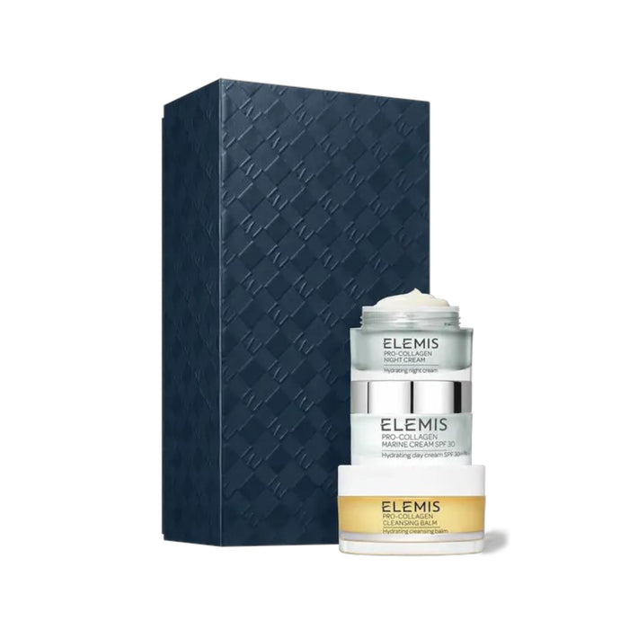 A dark textured rectangular box stands beside three stacked skincare containers labeled "ELEMIS." The ELEMIS - PRO-COLLAGEN HEROES GIFT SET by ELEMIS - STEINER includes a cleansing balm, day cream, and night cream for hydration.