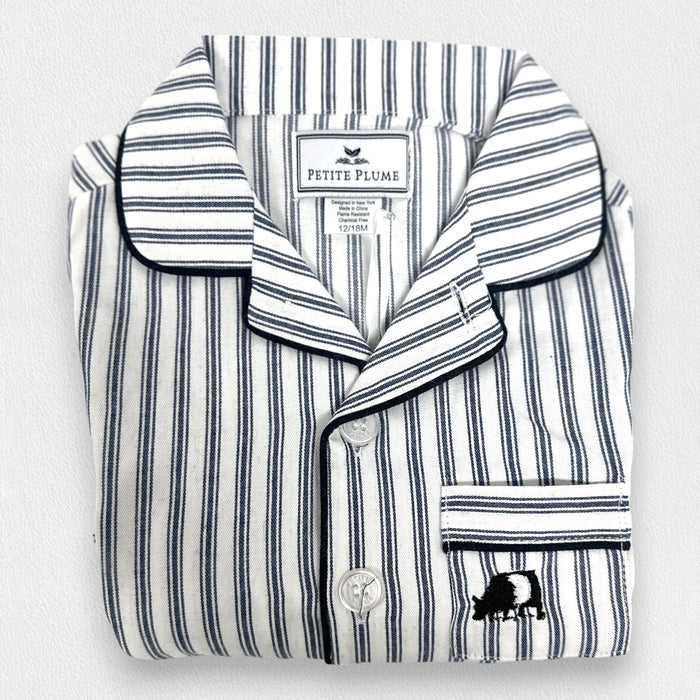 The PETITE PLUME FEARRINGTON LIFESTYLE COLLECTION - CHILDREN'S TWILL NAVY FRENCH TICKING PAJAMA SET is a delightful option for kids, featuring long sleeves and pants with chic vertical white and gray stripes. This set is crafted from yarn-dyed cotton, boasting a top with a collar, full button-down front, and a single chest pocket adorned with matching fabric piping along the cuffs and pocket opening.