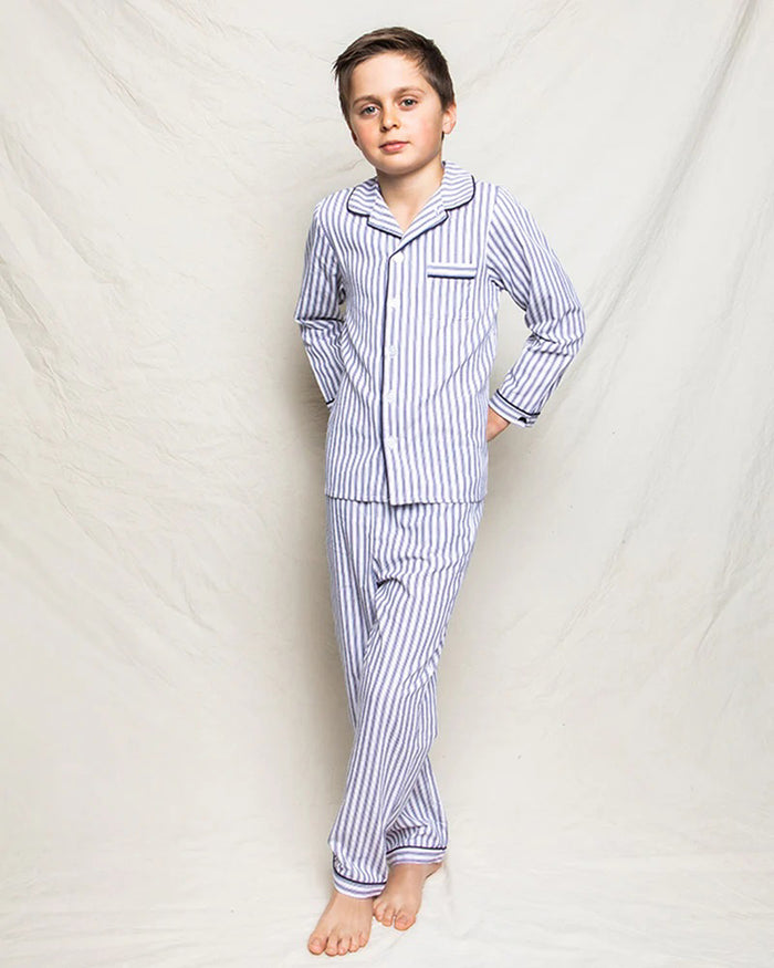 The PETITE PLUME FEARRINGTON LIFESTYLE COLLECTION - CHILDREN'S TWILL NAVY FRENCH TICKING PAJAMA SET is a delightful option for kids, featuring long sleeves and pants with chic vertical white and gray stripes. This set is crafted from yarn-dyed cotton, boasting a top with a collar, full button-down front, and a single chest pocket adorned with matching fabric piping along the cuffs and pocket opening.