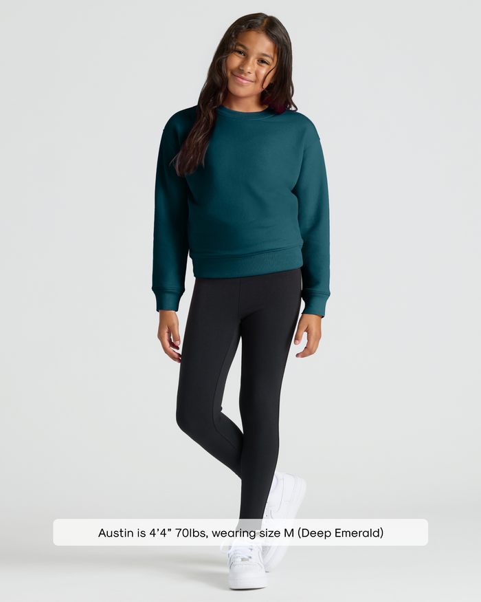Child wearing Girls Deep Emerald Slouch Pullover Crew with leggings and sneakers.
