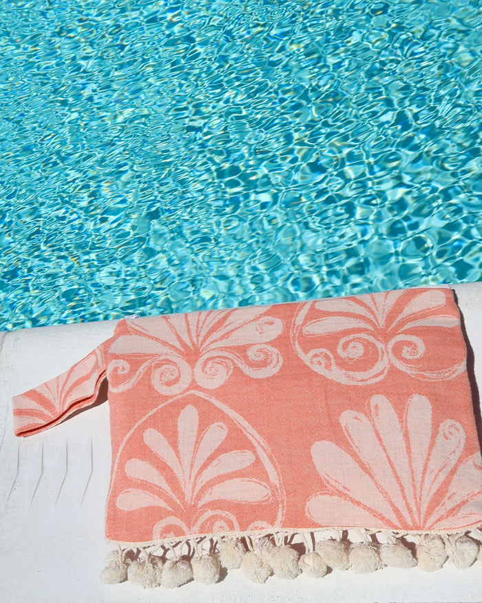 Coral floral print wet dry clutch bag with cream pom pom trim at the pool made in Greece. Greek brand Aeliea Anna wet dry beach bag water-resistant for summer and vacation