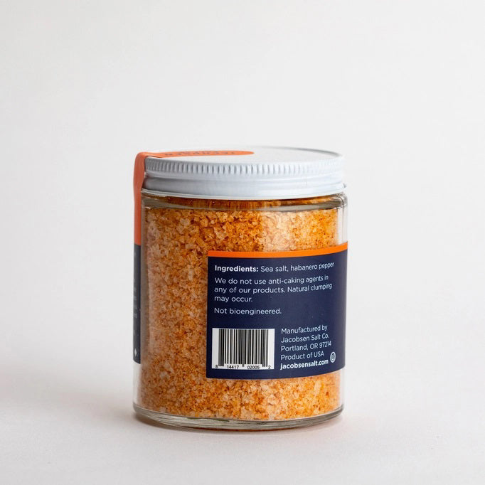 A small jar of JACOBSEN SALT CO. JACOBSEN SALT - INFUSED HABANERO SALT with a white lid sits on a light-colored surface against a plain, light gray background, ideal as spicy salt or for rimming cocktails.
