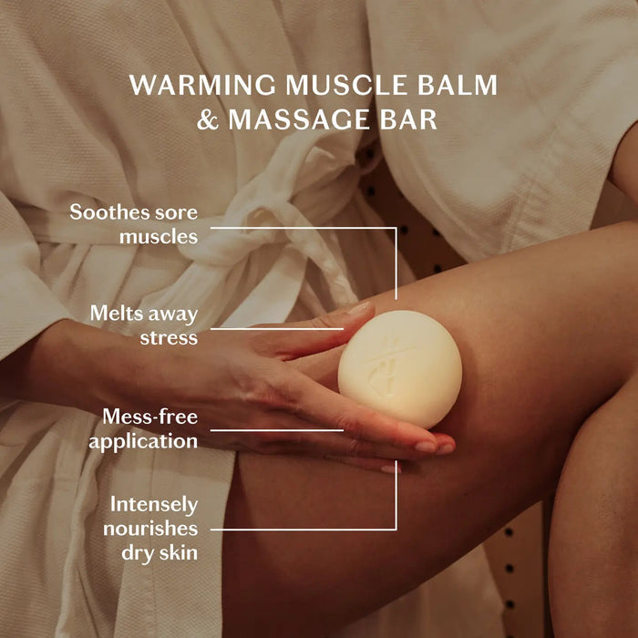 A round, white body stone wrapped in beige fabric sits beside a green and yellow box labeled "KATE MCLEOD - RECOVERY STONE | SOOTHING MUSCLE BALM," with ingredients and product details printed on the front.