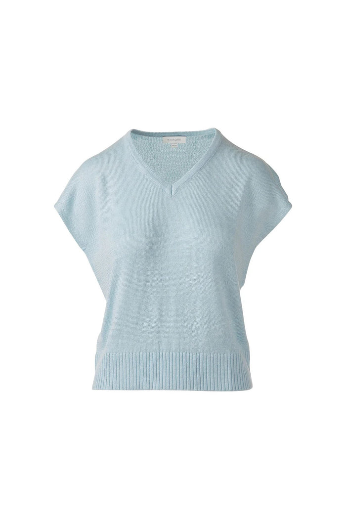 A woman in the KINROSS CASHMERE Cap Sleeve Vee Neck Linen Sweater with blue, brown, and tan stripes and white pants smiles softly against a plain white background.