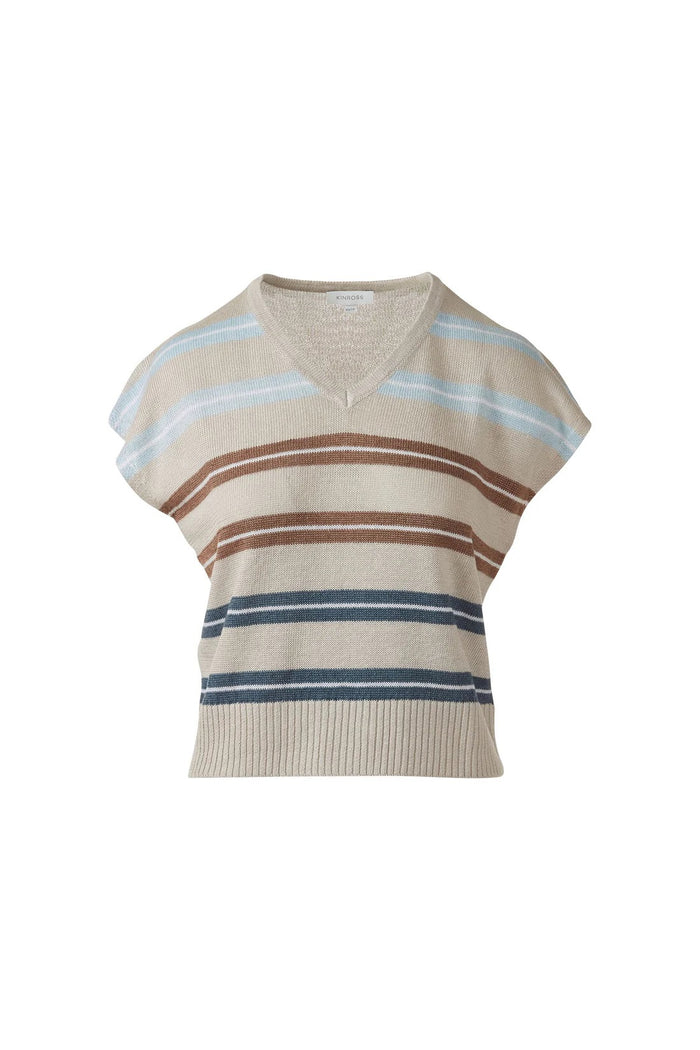 A woman in the KINROSS CASHMERE Cap Sleeve Vee Neck Linen Sweater with blue, brown, and tan stripes and white pants smiles softly against a plain white background.