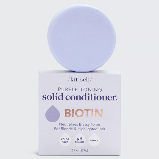 A KITSCH Purple Toning Solid Conditioner Bar sits on its packaging, which states it's formulated with Biotin for blonde and highlighted hair, neutralizing brassiness. The labels affirm it's color safe, pH balanced, and vegan.