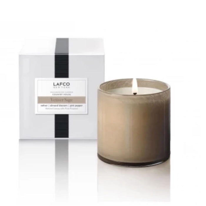 A hand-poured LAFCO Vetiver Sage candle in a frosted glass jar sits beside its white box packaging, creating the perfect luxury accent for any room.