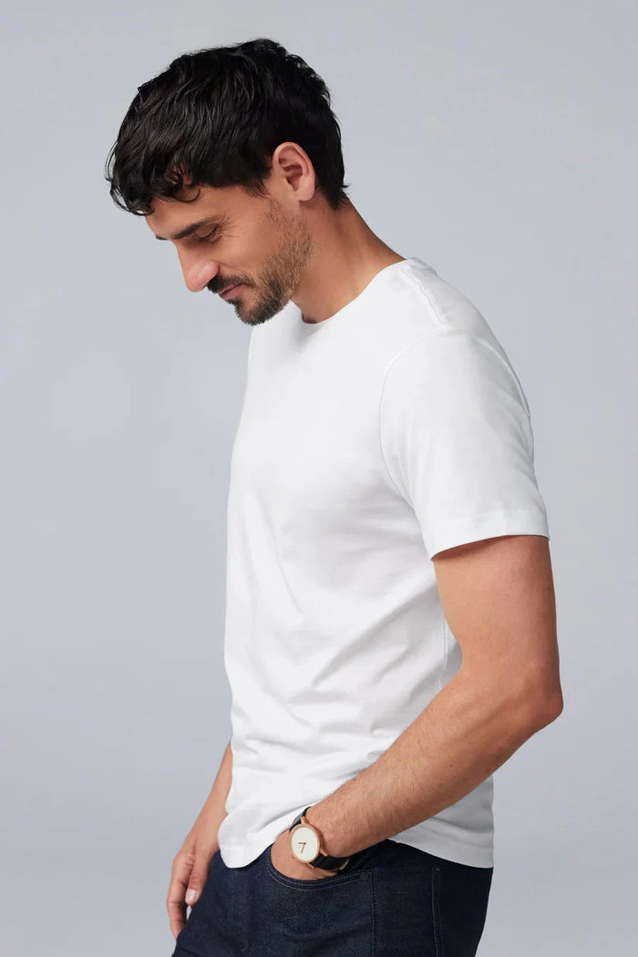 A man with short dark hair and a beard wears a MACK WELDON SILVER CREW NECK T-SHIRT and a black watch, standing against a light gray background with a neutral expression.