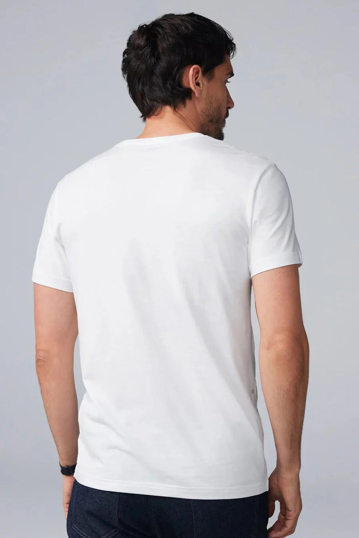 A man with short dark hair and a beard wears a MACK WELDON SILVER CREW NECK T-SHIRT and a black watch, standing against a light gray background with a neutral expression.
