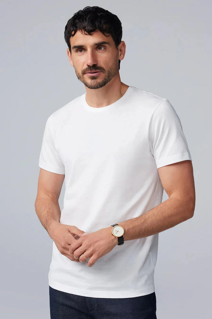 A man with short dark hair and a beard wears a MACK WELDON SILVER CREW NECK T-SHIRT and a black watch, standing against a light gray background with a neutral expression.