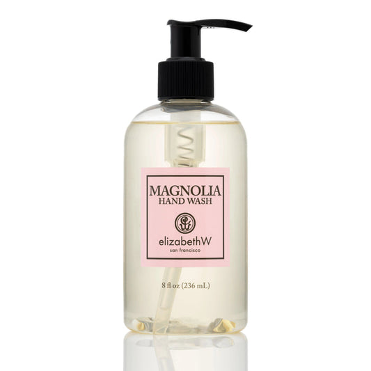 An 8 fl oz (236 mL) clear plastic pump bottle of MAGNOLIA HAND WASH by E WIGHTMAN & CO features a pink-bordered label with black text, offering an elegant botanical hand wash.