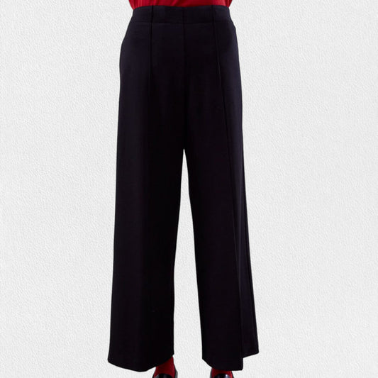 A person wearing MEIMEIJ PULL ON STRAIGHT LEG LONG PANTS in black and a red top, shown from the waist down, stands against a light textured background.
