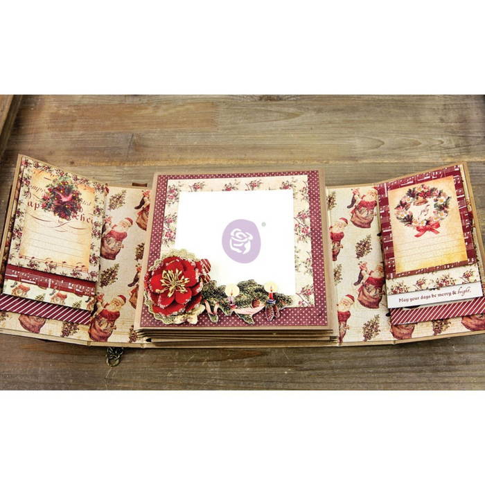 An open vintage-style paper album or scrapbook book displayed on a wooden surface, showing multiple decorated interior pages with floral and holiday-themed designs.