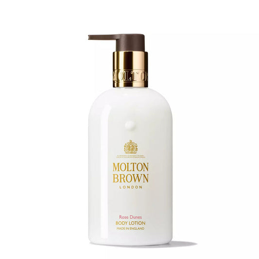 A white bottle of MOLTON BROWN Rose Dunes Body Lotion with a gold pump and label, shown on a plain white background. This moisturising lotion hydrates skin with a luxurious ambery-rose fragrance.