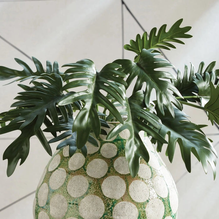 The NAPA HOME AND GARDEN - SPLIT LEAF SELLOUM STEM LARGE features two tropical green leaves with long stems, offering a glossy texture akin to realistic philodendrons. Ideal for home decor, these artificial leaves are displayed against a white background for an authentic look.