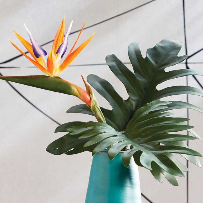 The NAPA HOME AND GARDEN - SPLIT LEAF SELLOUM STEM LARGE features two tropical green leaves with long stems, offering a glossy texture akin to realistic philodendrons. Ideal for home decor, these artificial leaves are displayed against a white background for an authentic look.