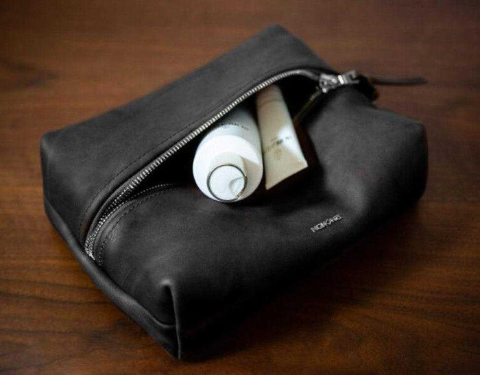 Open black leather dopp kit with toiletries inside for travel