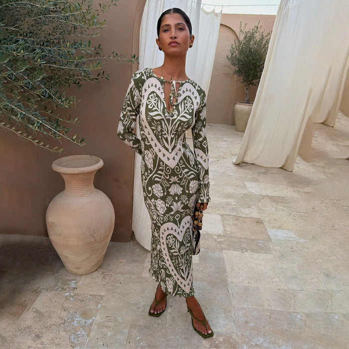 Olive Amara Plisse Gaia Dress in a green floral and heart print, with long sleeves and a tie neckline.