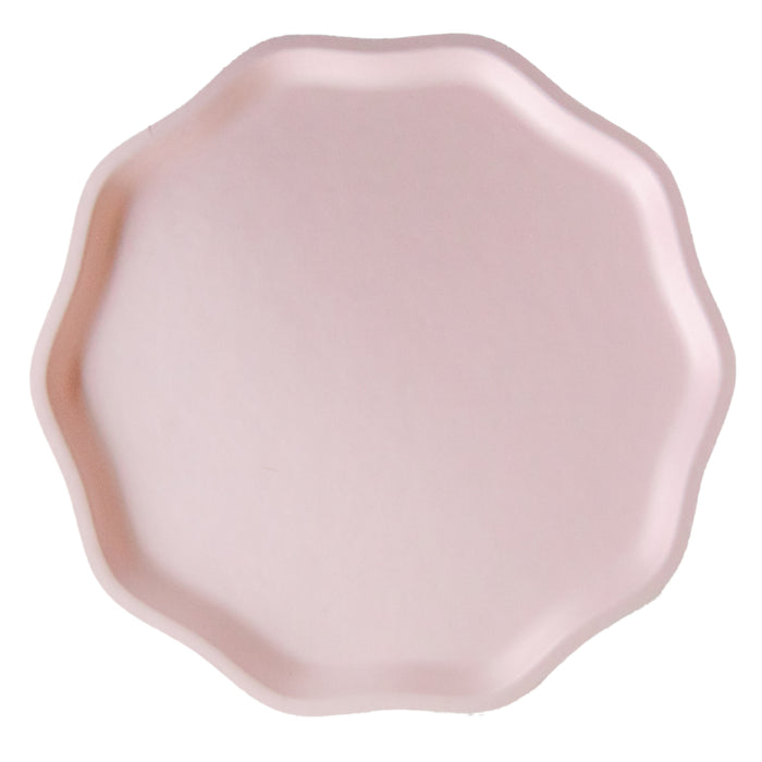 Pink compostable plate with a scalloped edge on a white background.