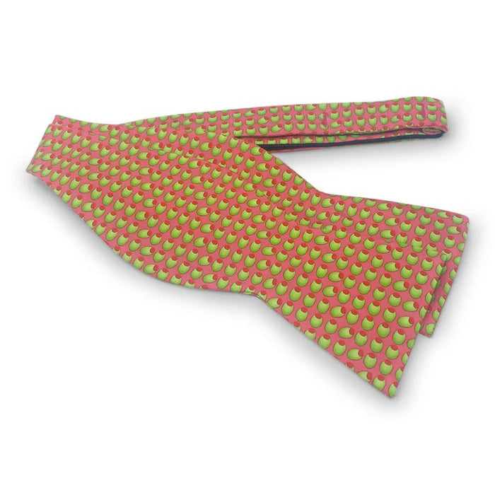 The PETER-BLAIR Olives Silk Bow Tie in Coral by BIRD DOG BAY features a playful olive pattern on coral 100% silk and includes an adjustable neck for a perfect fit.