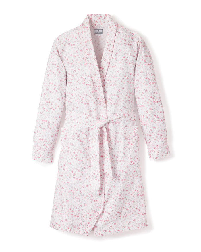 The PETITE PLUME - DORSET FLORAL ROBE by PETITE PLUME is a long-sleeved, knee-length cotton robe with a light pink and white floral pattern, shawl collar, and matching belt. Lightweight sleepwear shown on a white background.
