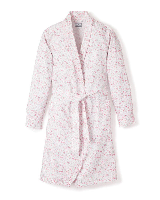 The PETITE PLUME - DORSET FLORAL ROBE by PETITE PLUME is a long-sleeved, knee-length cotton robe with a light pink and white floral pattern, shawl collar, and matching belt. Lightweight sleepwear shown on a white background.