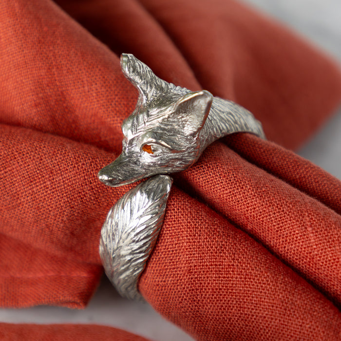 Silver fox-shaped ring around an orange napkin.